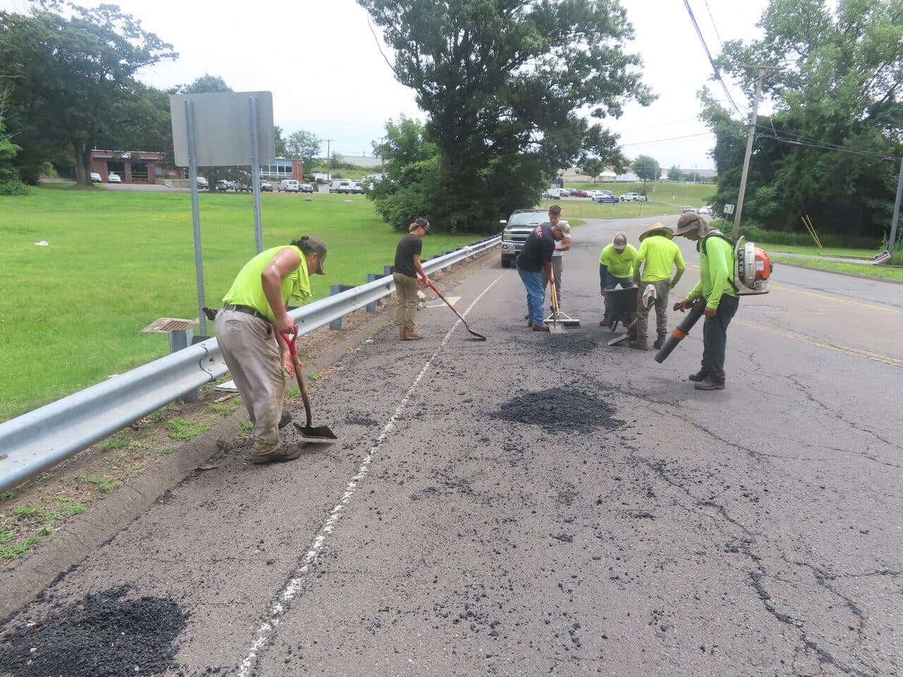 Commercial Parking Lot Paving project in Orange, CT — workers filling potholes along guardrail
