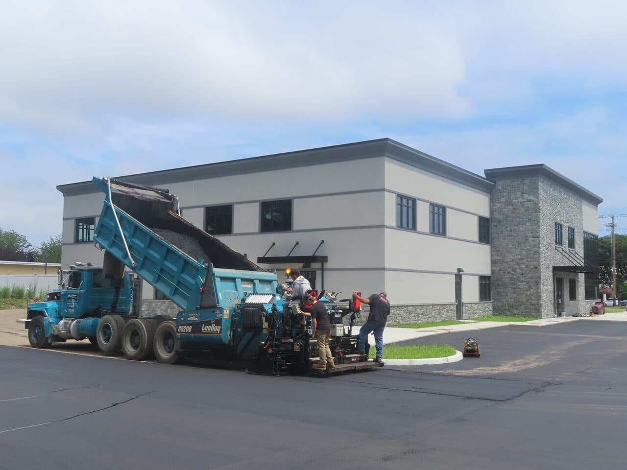 Commercial Parking Lot Paving project in Orange, CT — paver and dump truck at new office building