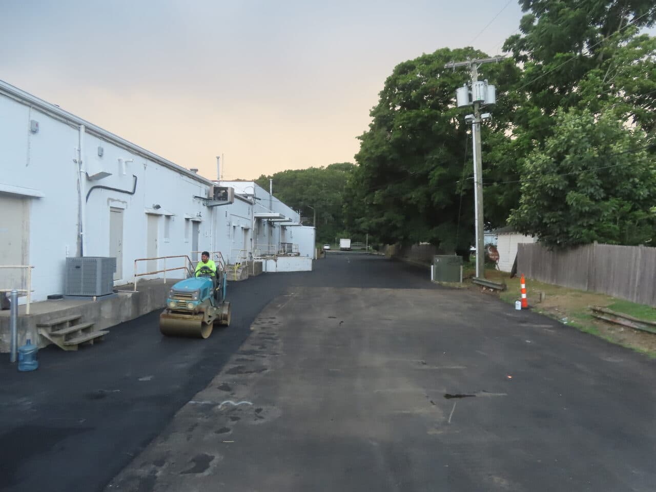 Commercial Parking Lot Paving project in Branford, CT — roller compacting fresh asphalt at dusk