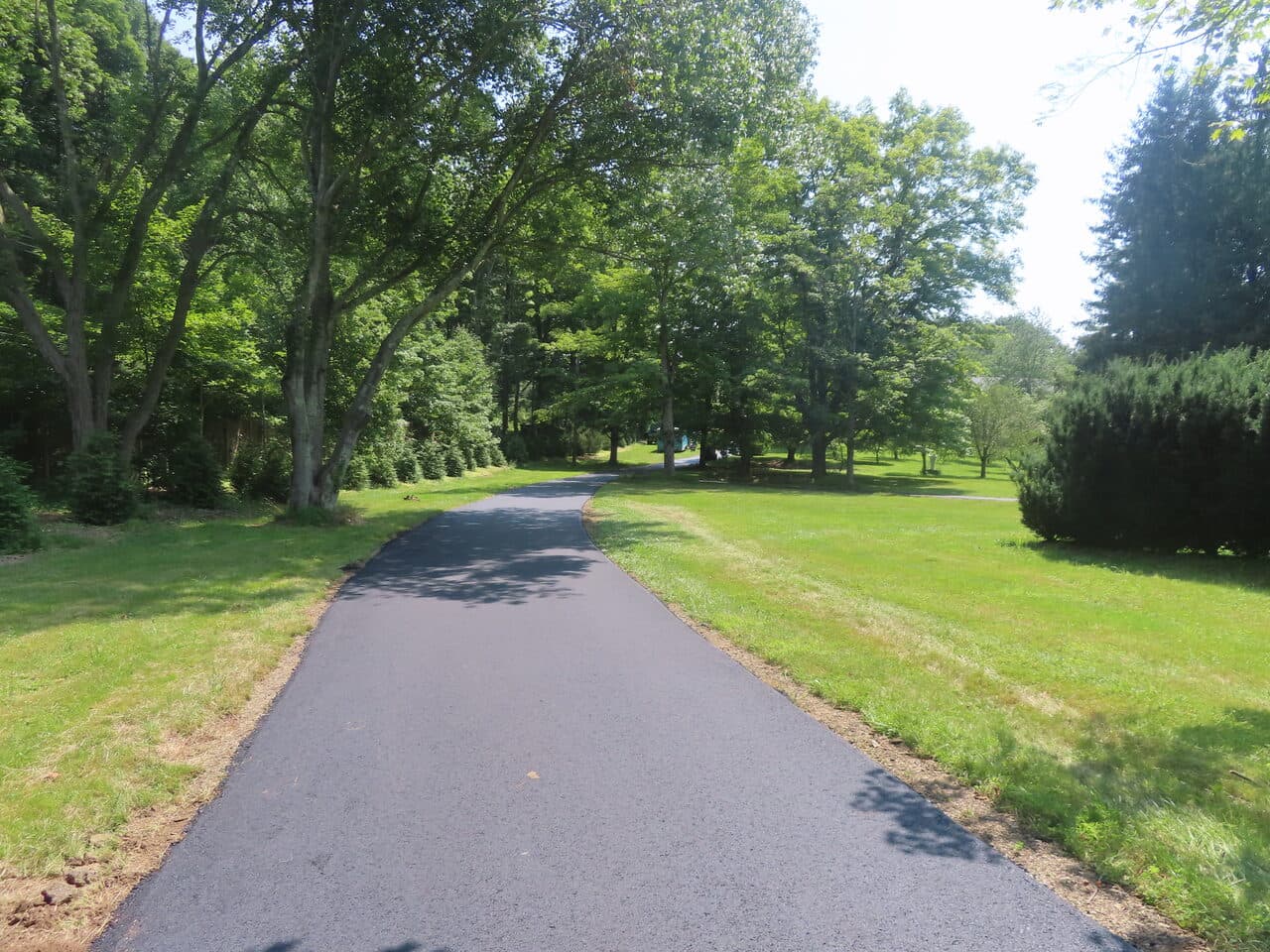 Pedestrian Trail & Parking Lot Paving project in Guilford, CT — wide paved drive through lawn