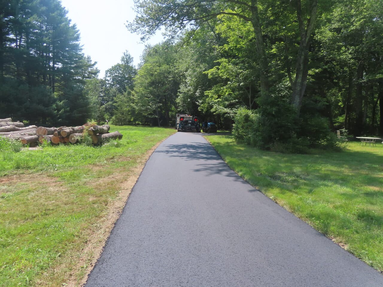Pedestrian Trail & Parking Lot Paving project in Guilford, CT — paved drive past log pile
