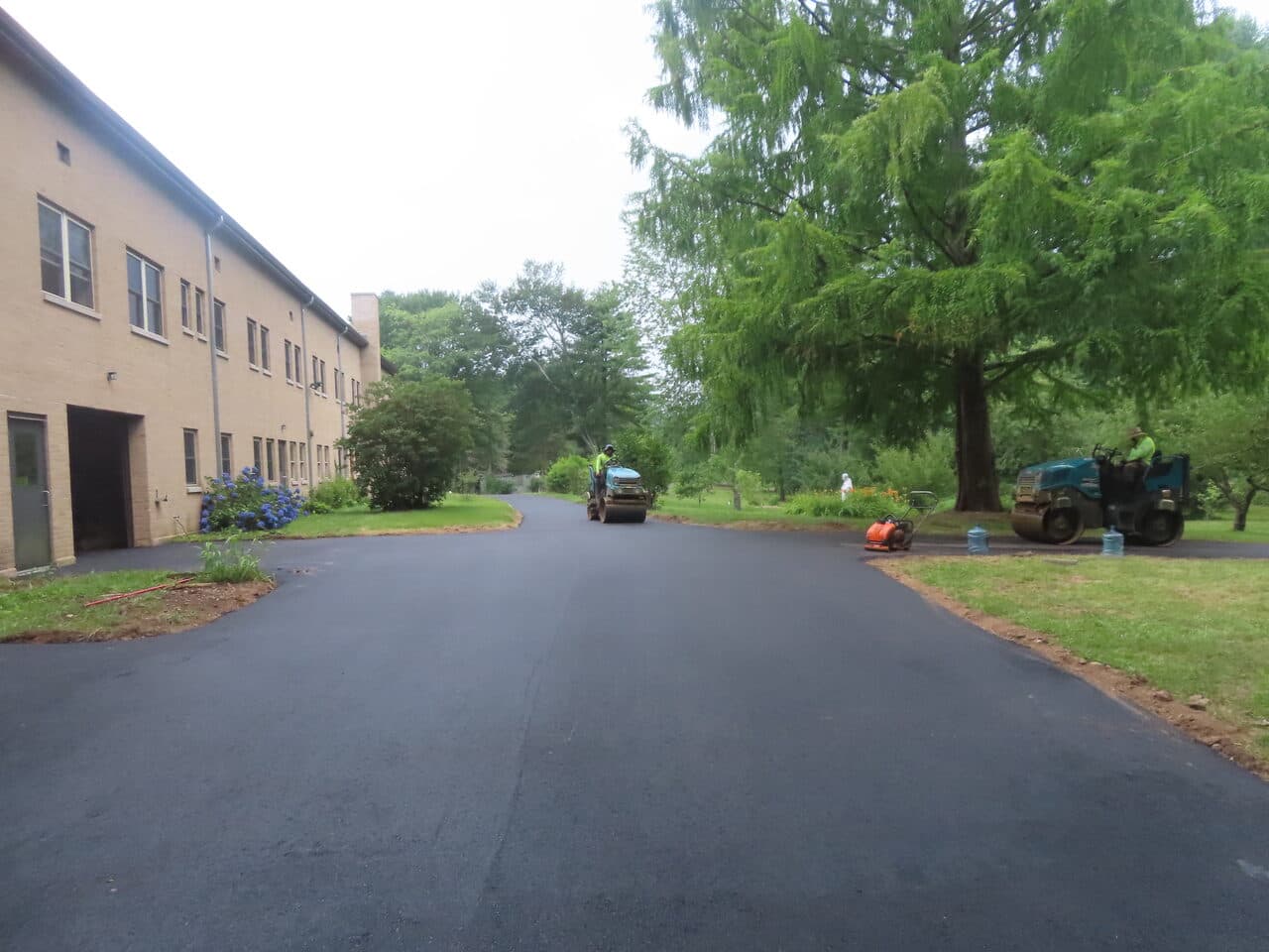 Pedestrian Trail & Parking Lot Paving project in Guilford, CT — roller paving lot beside building
