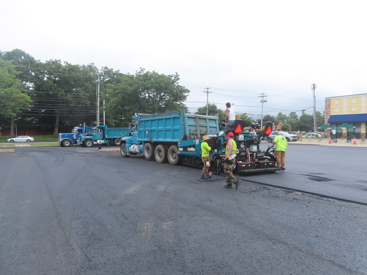 Commercial Parking Lot Paving project in Shelton, CT — paver train laying fresh asphalt