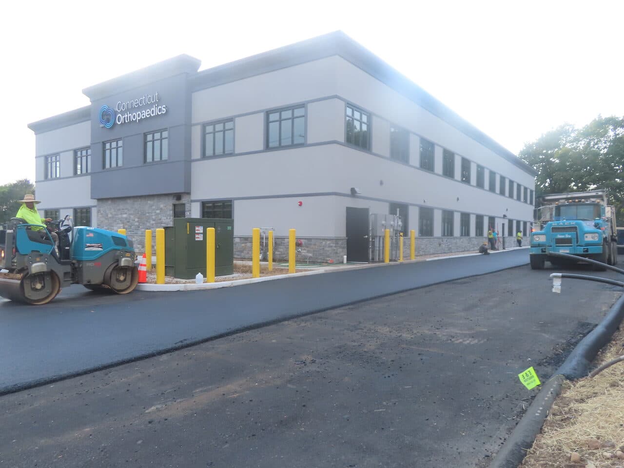 Commercial Parking Lot Paving project in Orange, CT — finished lot with roller and dump truck