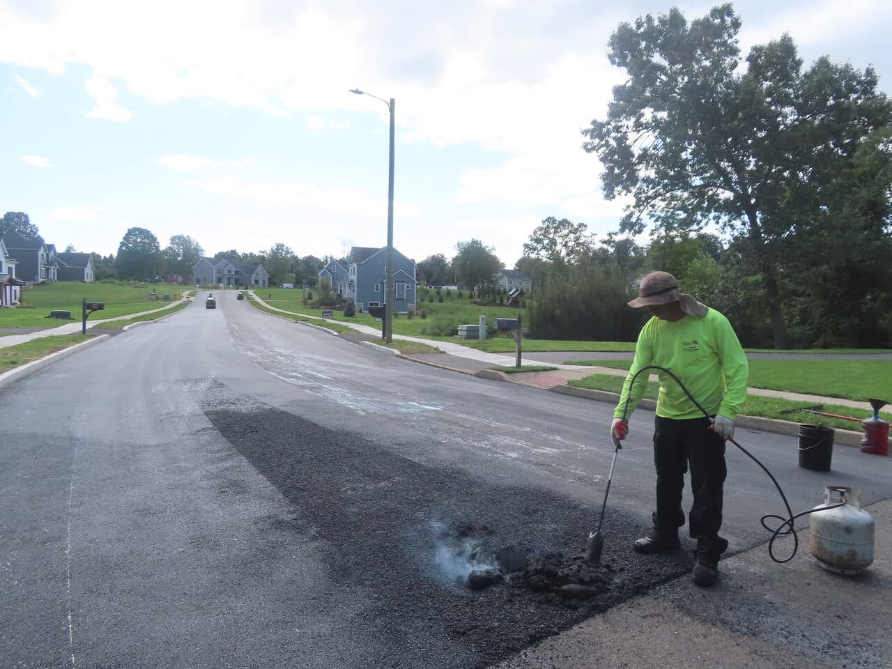 Roadway Paving project in Cheshire, CT — worker torching patch on road