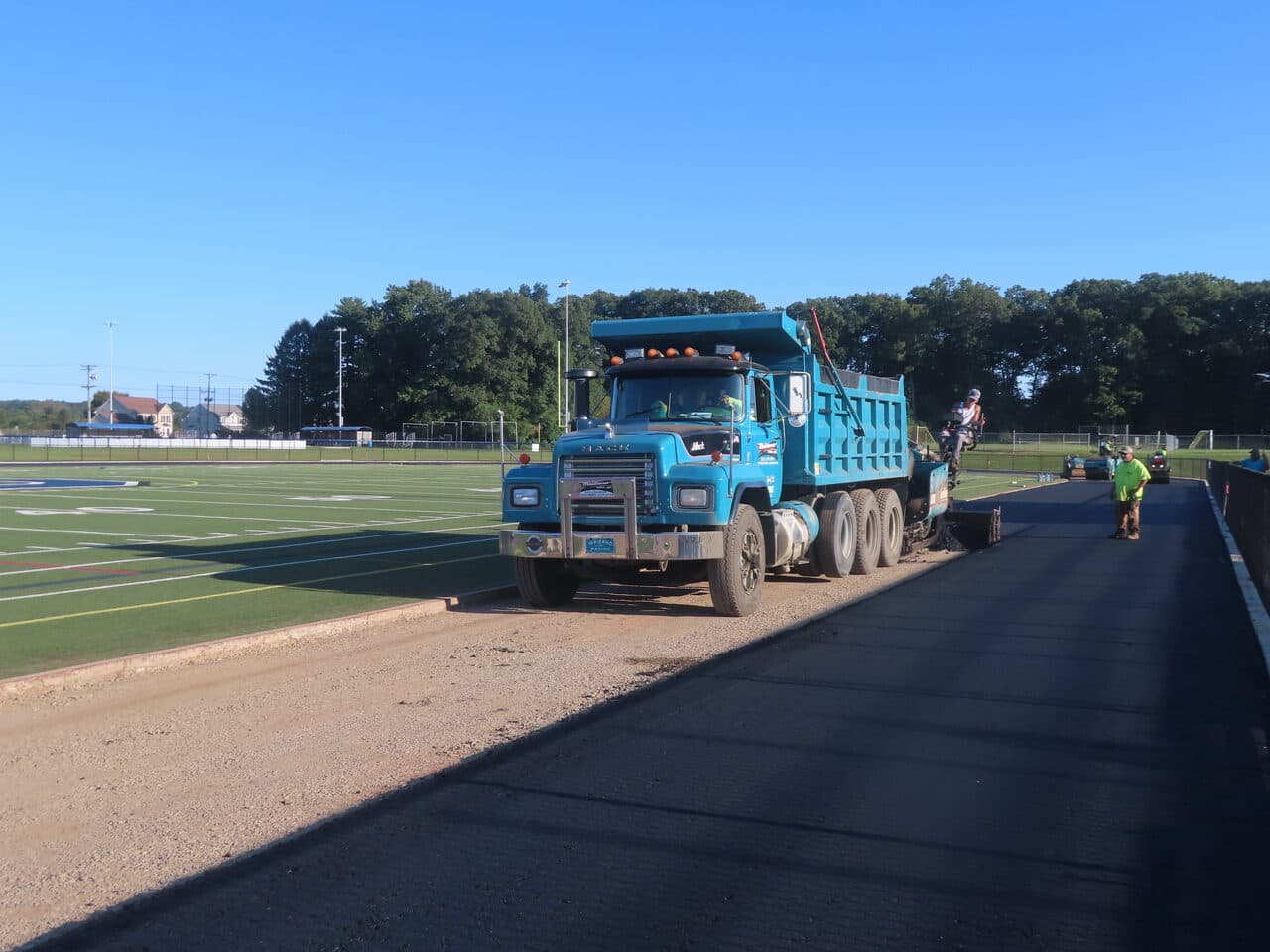 Athletic Surface Base Paving project in Southington, CT — dump truck feeding paver on track