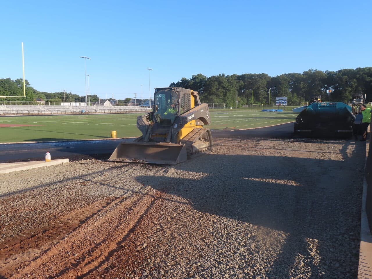 Athletic Surface Base Paving project in Southington, CT — skid steer spreading stone base