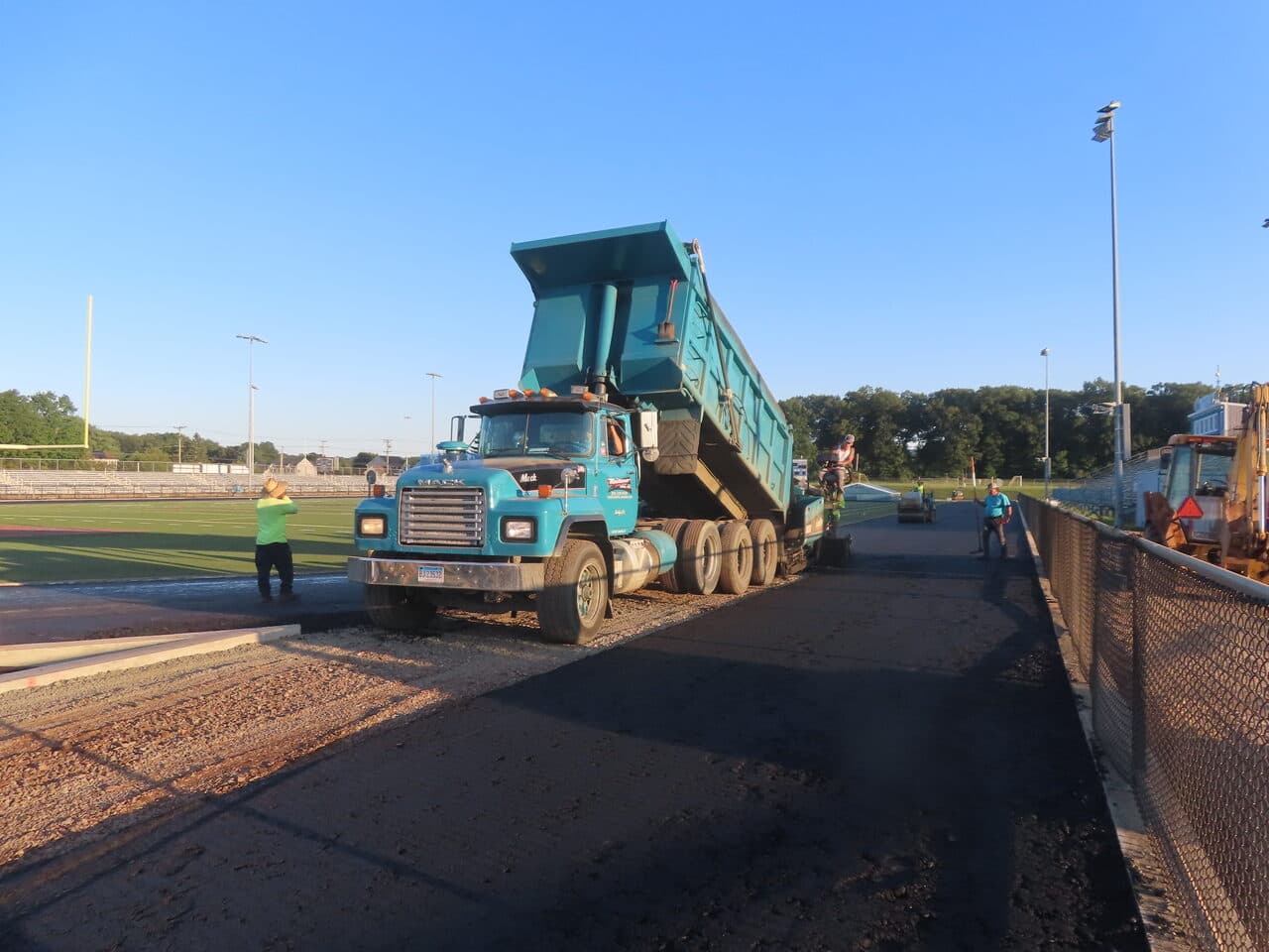 Athletic Surface Base Paving project in Southington, CT — dump truck spreading base on track
