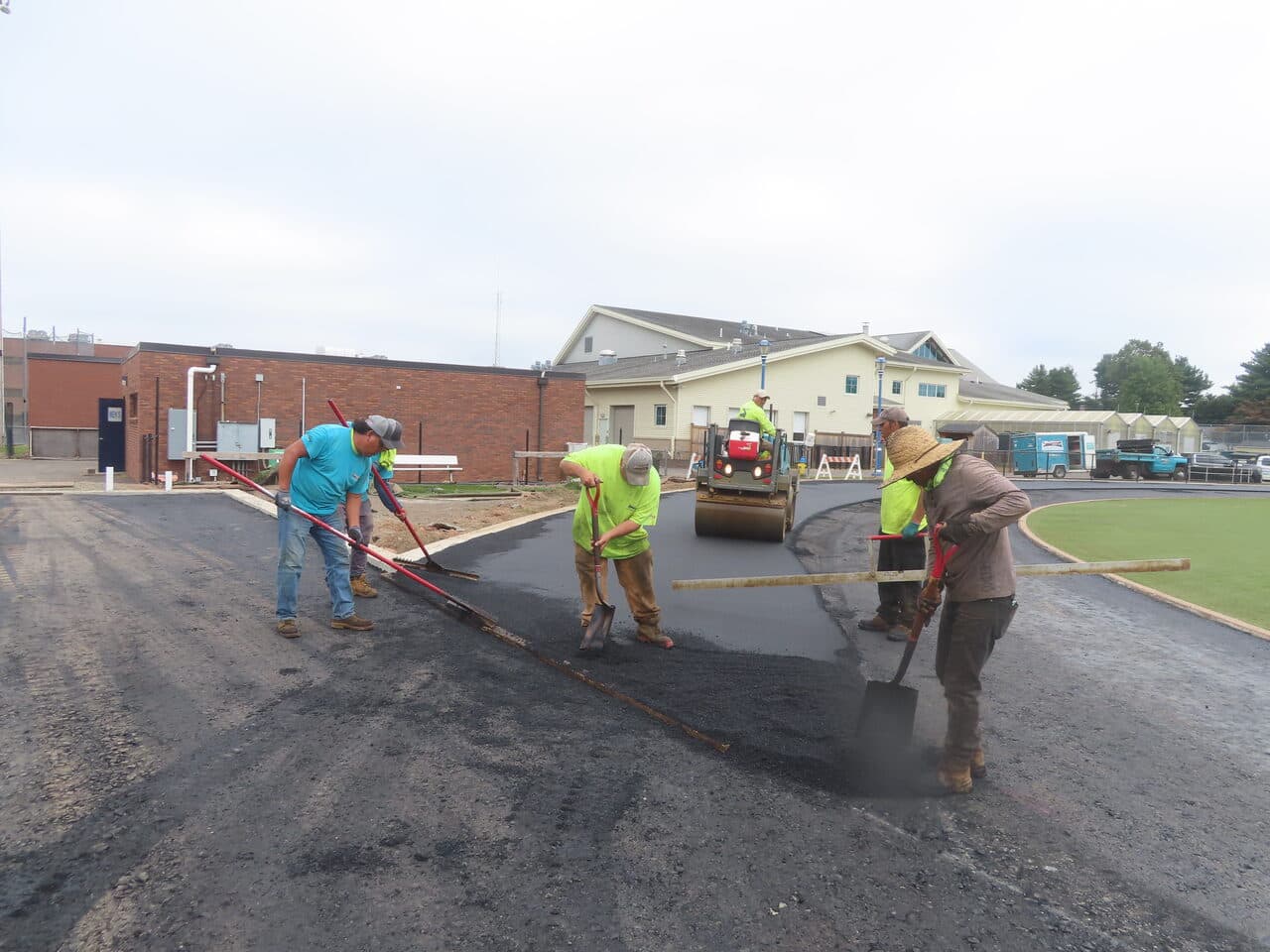 Athletic Surface Base Paving project in Southington, CT — crew raking asphalt with roller