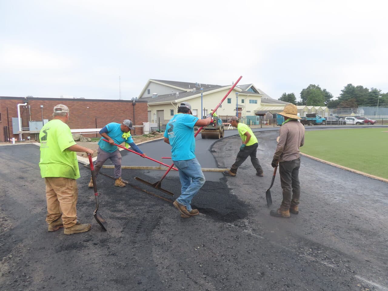 Athletic Surface Base Paving project in Southington, CT — crew spreading asphalt on curve