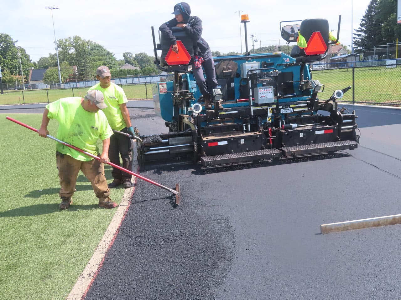 Athletic Surface Base Paving project in Southington, CT — paver detail with worker raking edge