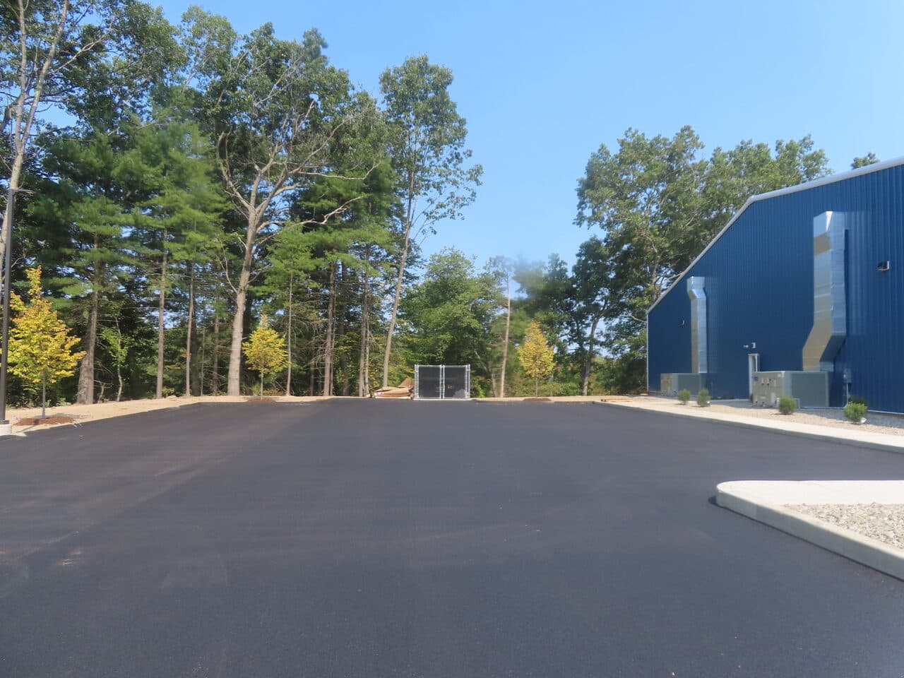 Commercial Parking Lot Paving project in Plainville, CT — fresh asphalt lot by blue building