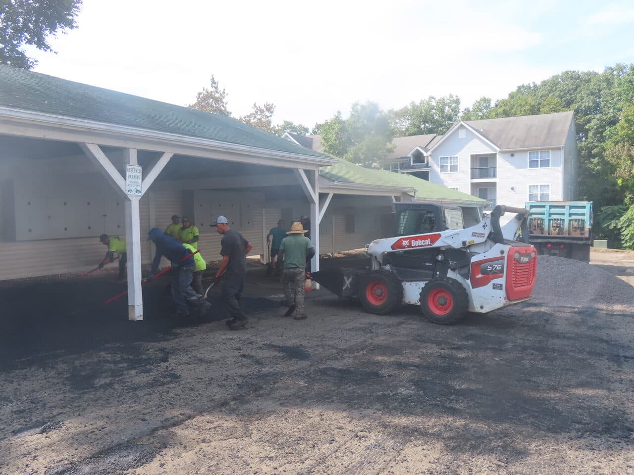 Commercial Parking Lot Paving project in Hamden, CT — crew raking asphalt under carport