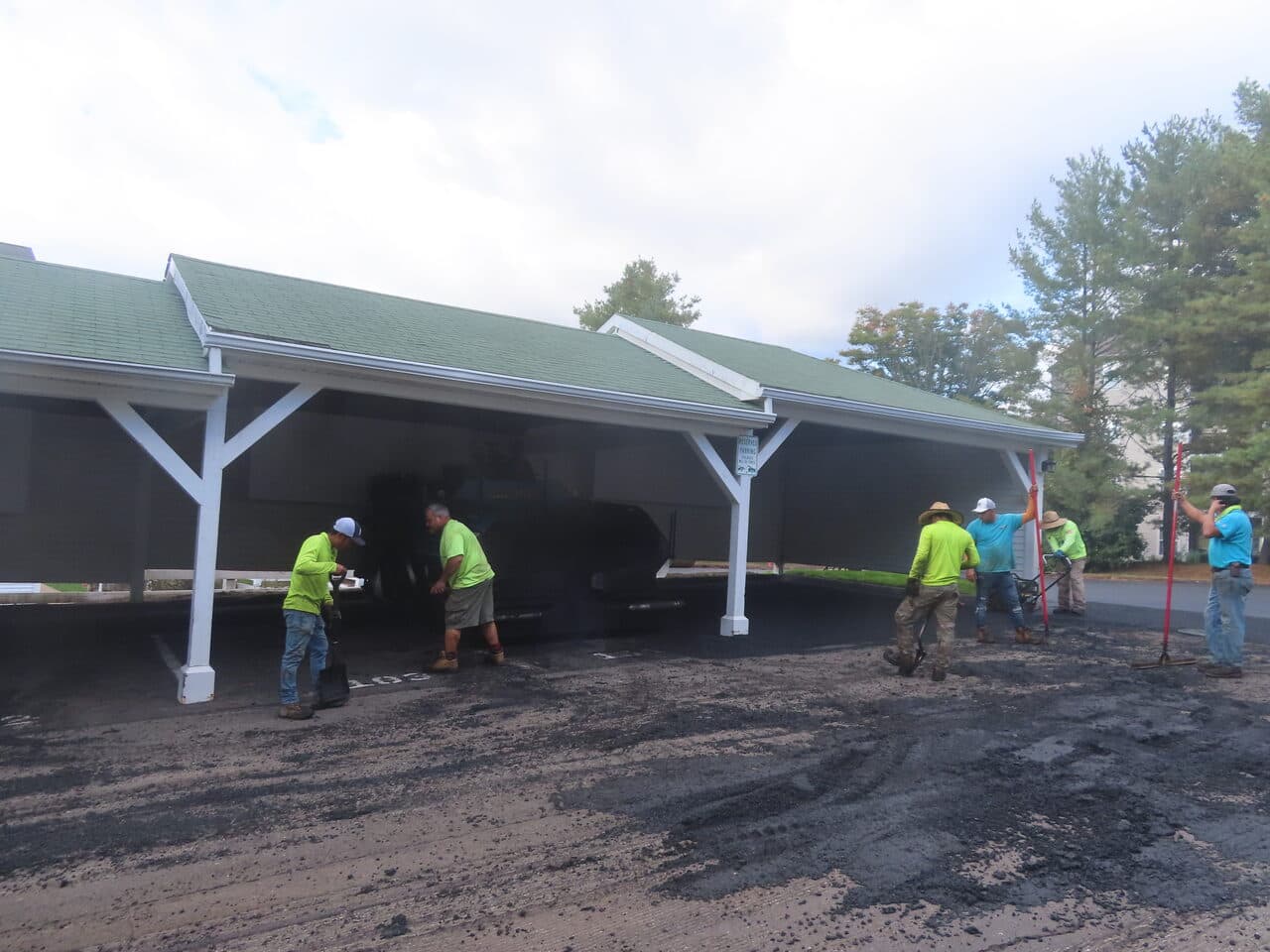 Commercial Parking Lot Paving project in Hamden, CT — crew raking around carport before paving