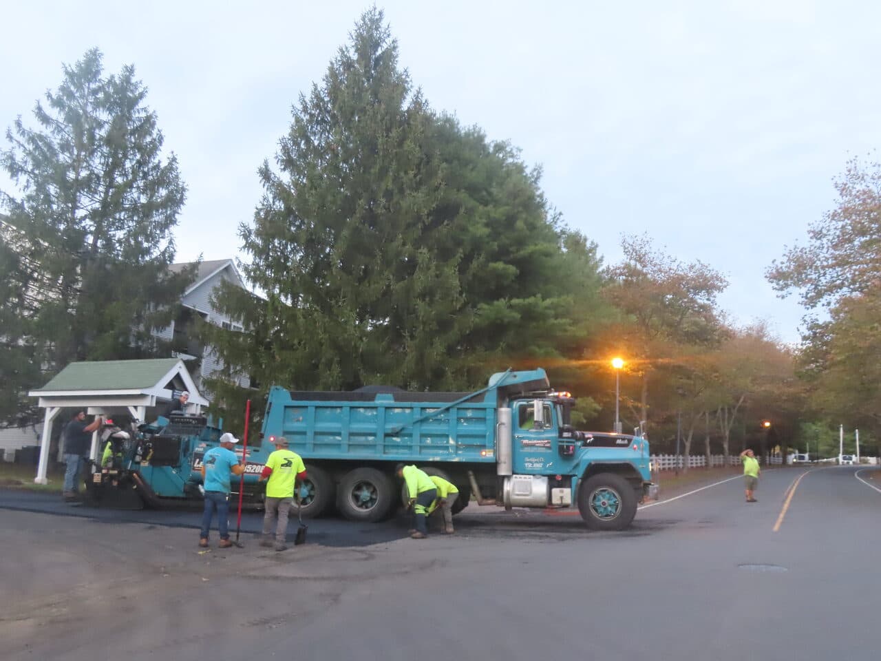 Commercial Parking Lot Paving project in Hamden, CT — paver and dump truck at dusk on road