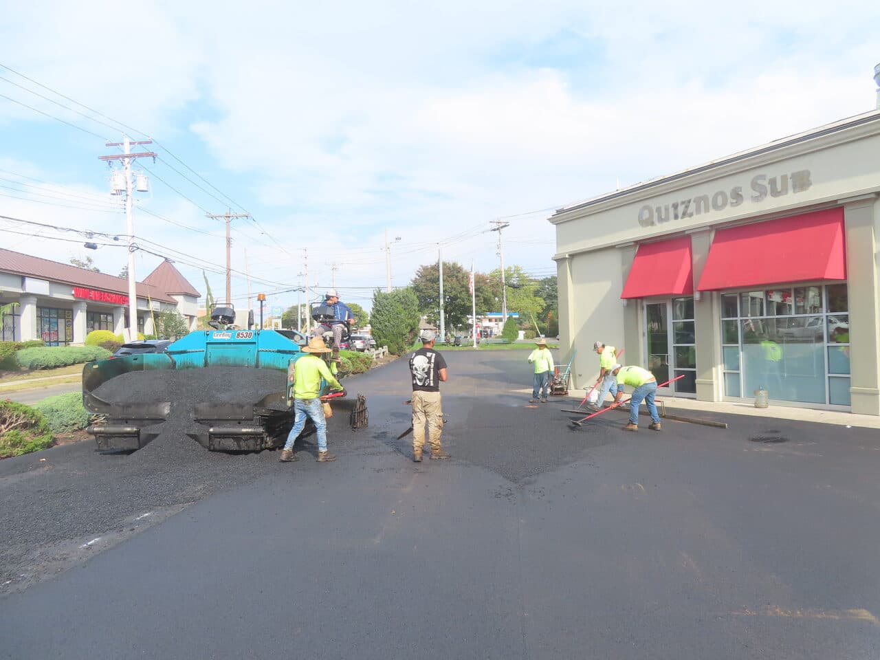 Commercial Parking Lot Paving project in Orange, CT — crew raking near paver at Quiznos
