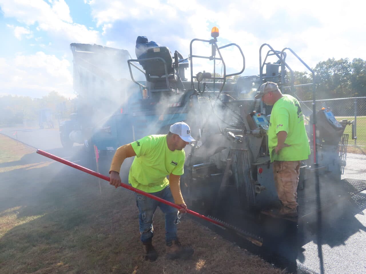 Athletic Surface Base Paving project in East Windsor, CT — workers raking behind paver