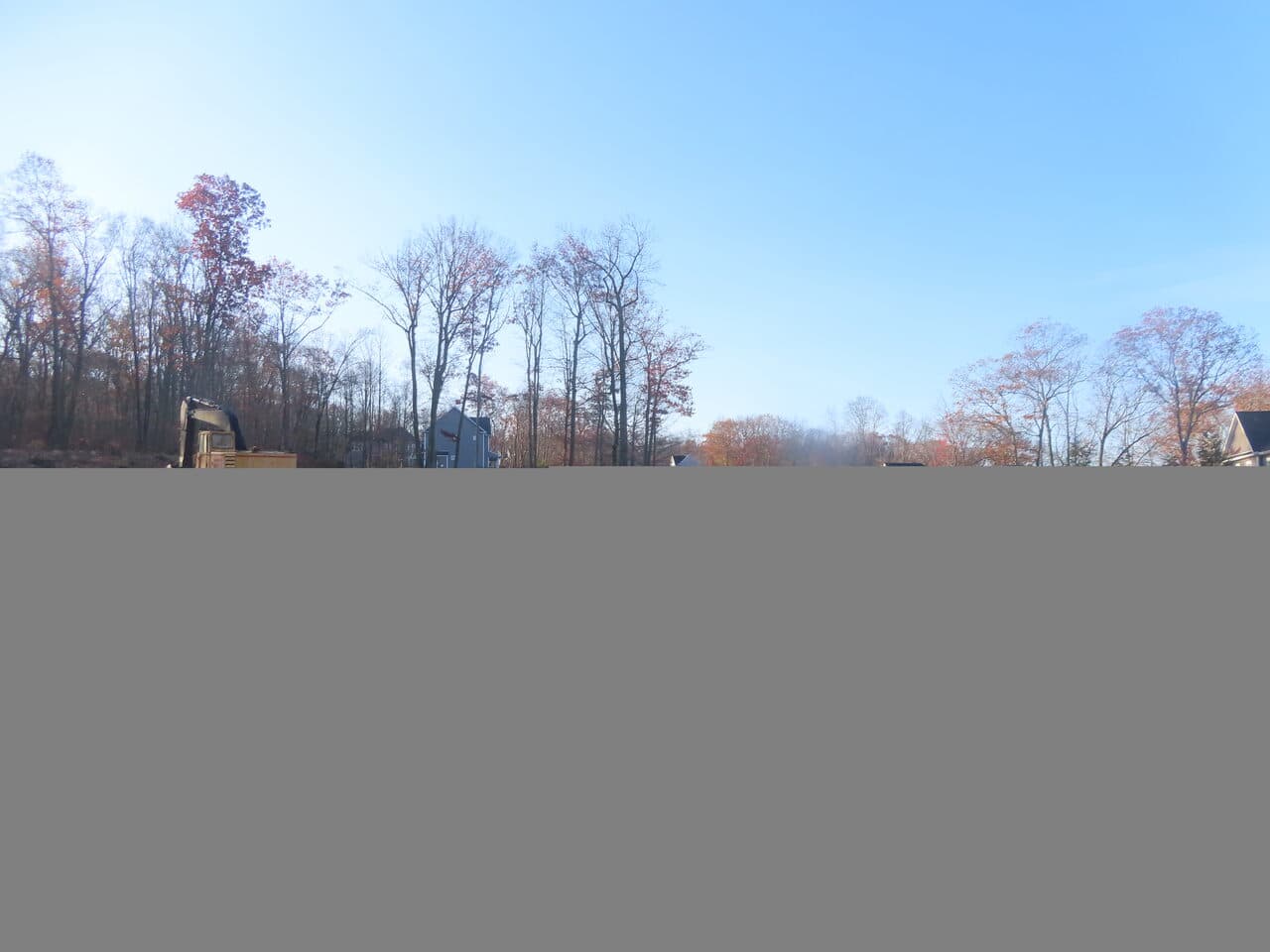 Roadway Paving project in Higganum, CT — cleared lot with excavator and houses