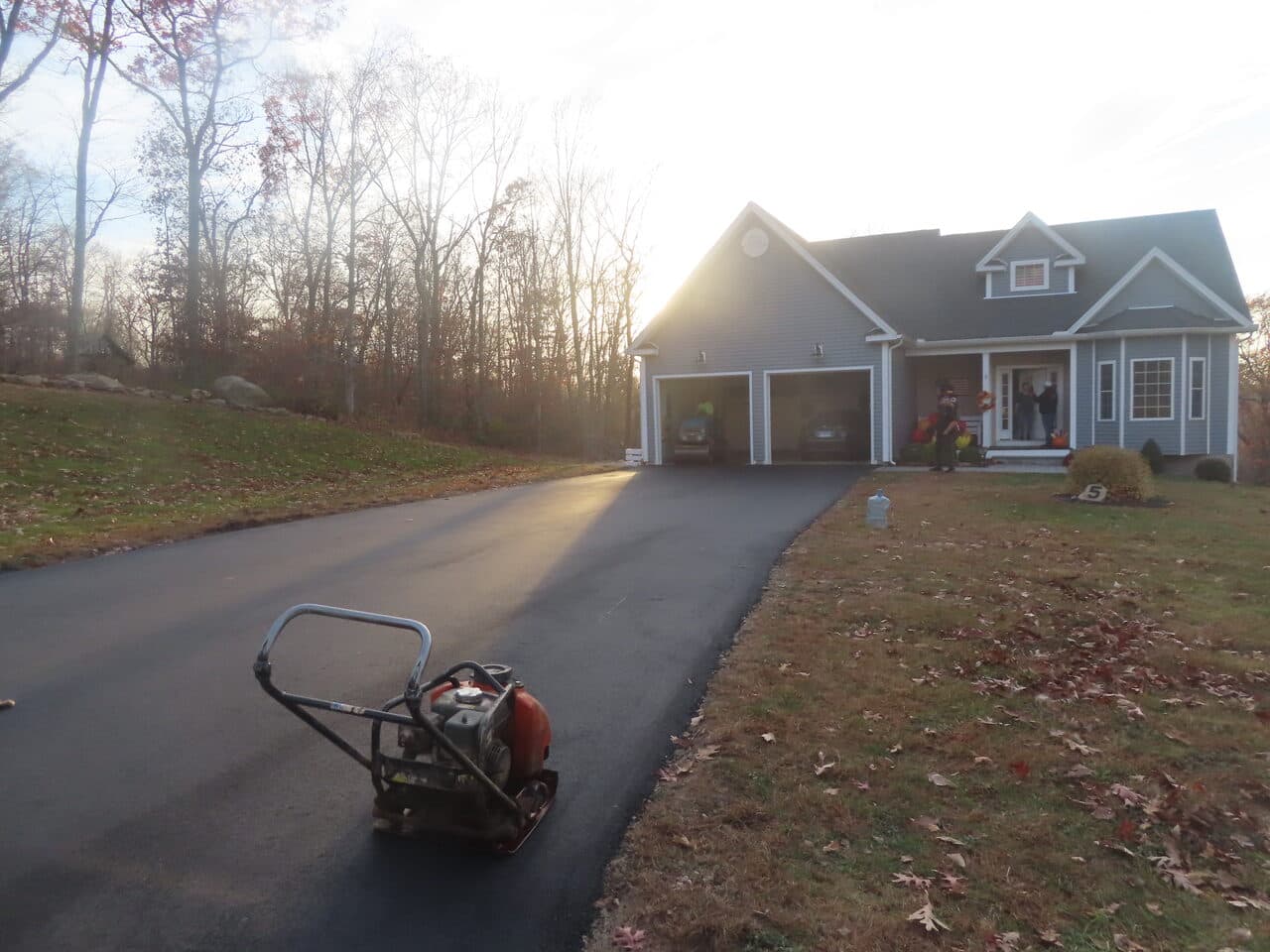 Residential Driveway Paving project in Stonington, CT — finished driveway with compactor and house