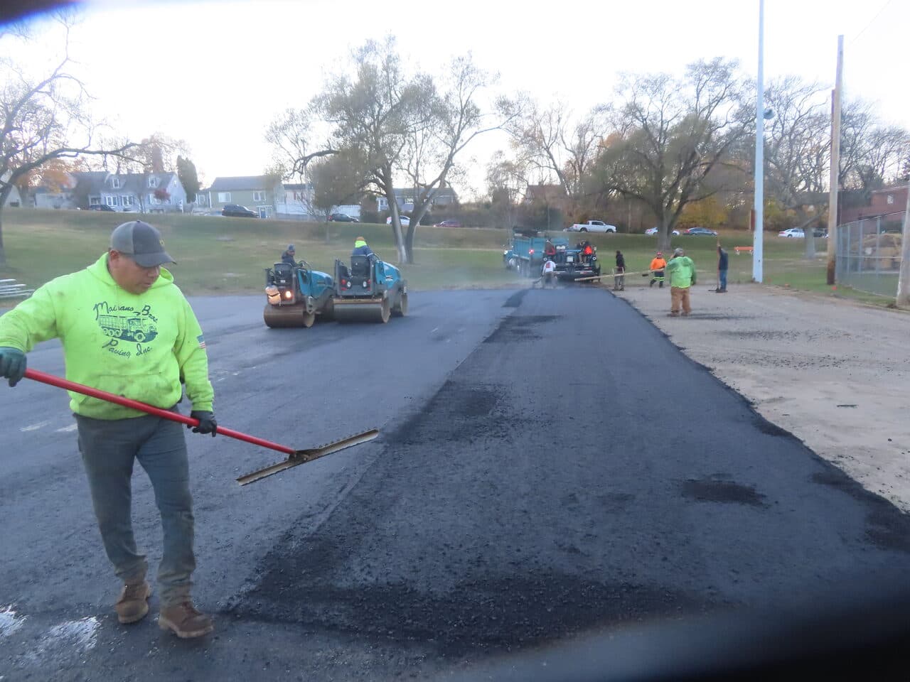 Commercial Parking Lot Paving project in Groton, CT — worker raking fresh asphalt with rollers