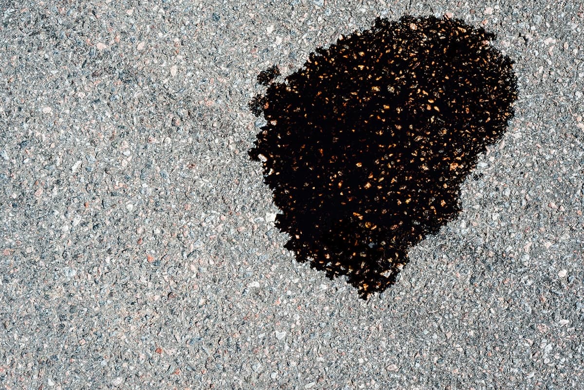 Oil puddle leak on asphalt driveway