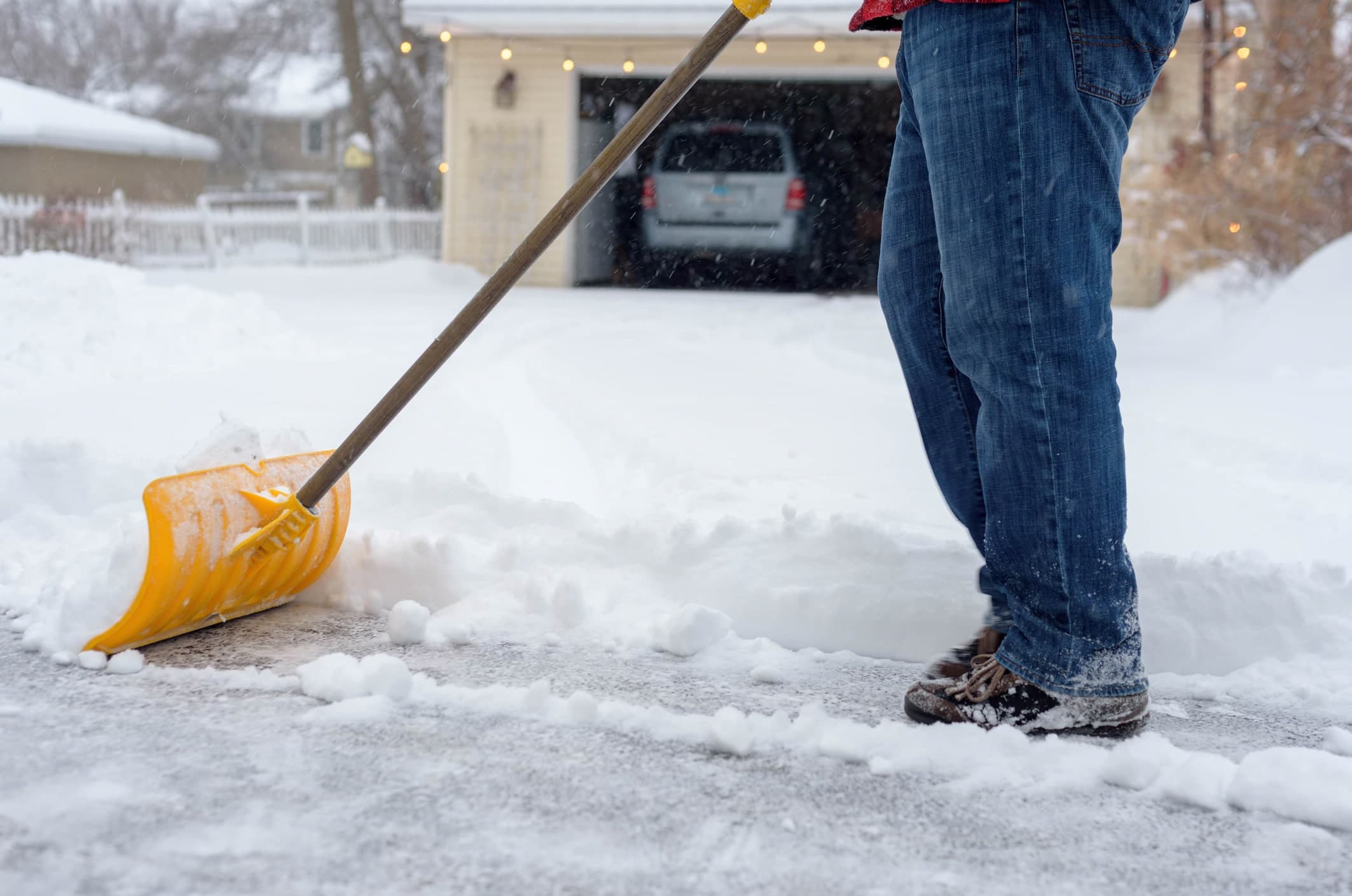 Shoveling snow on asphalt sidewalk in winter time before applying salt