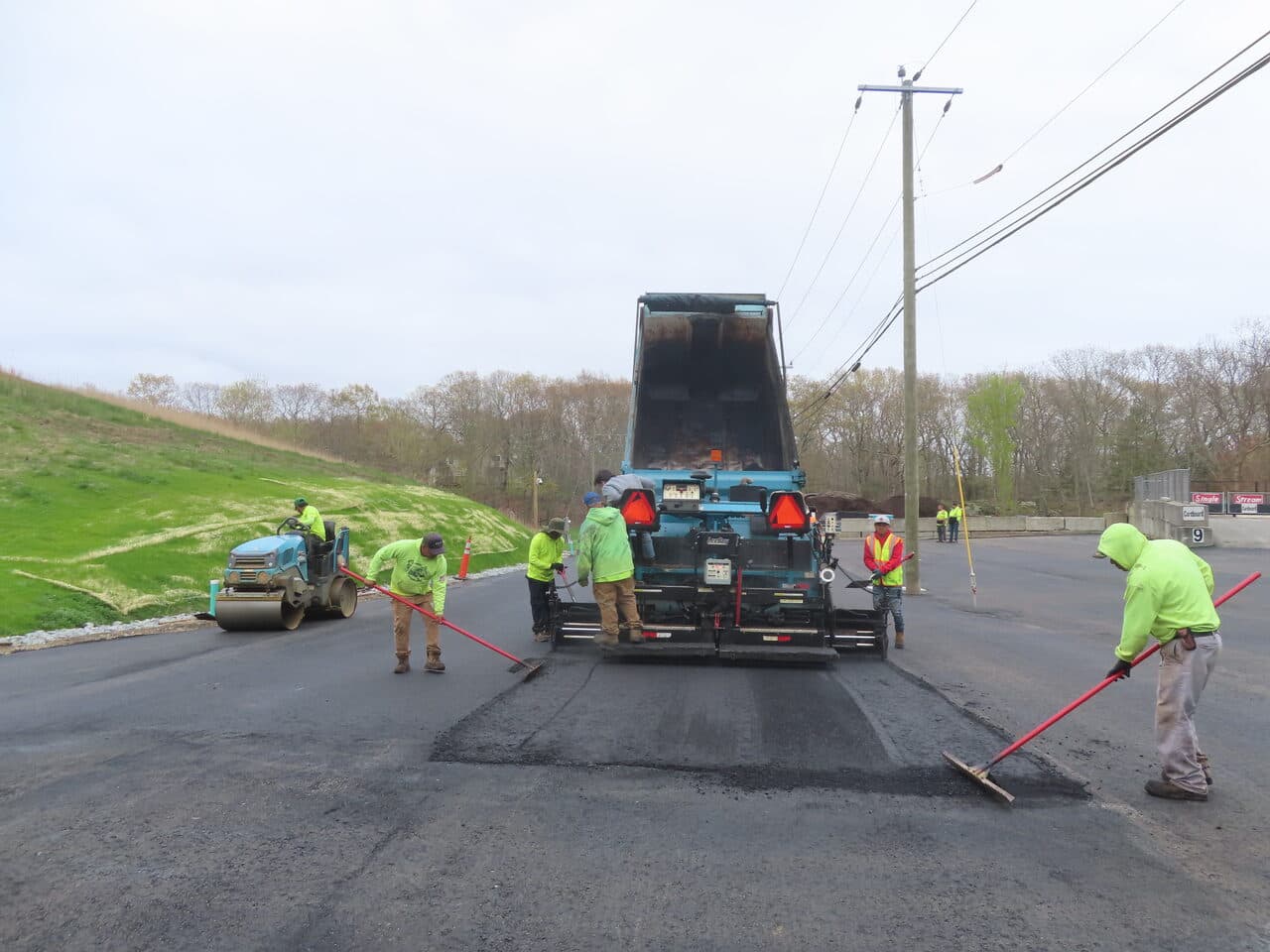 Commercial Parking Lot Paving project in East Lyme, CT — crew raking fresh asphalt behind paver