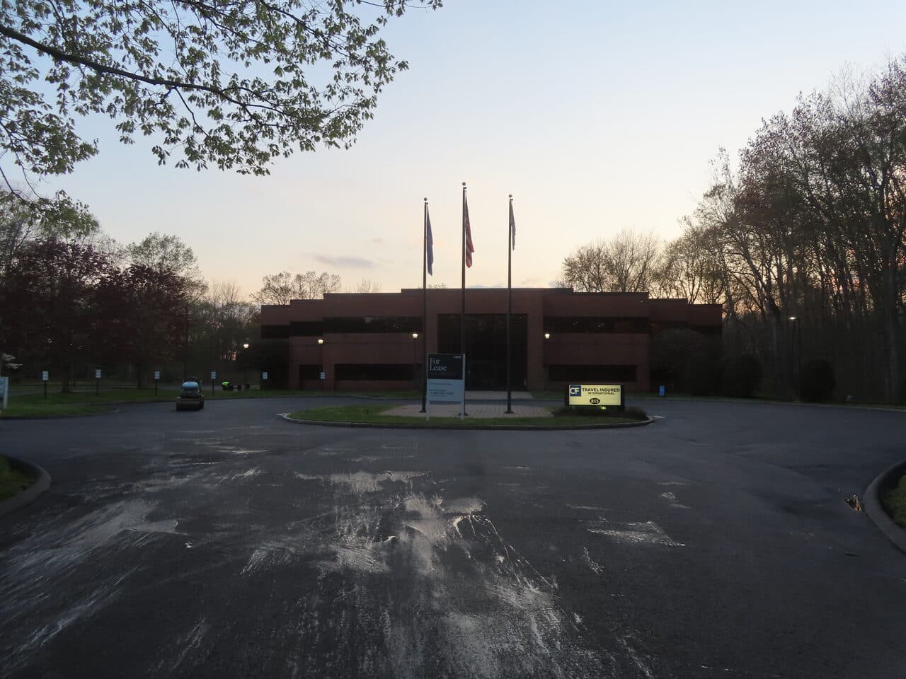 Commercial Sealcoating project in Glastonbury, CT — worn lot at dusk before sealcoat