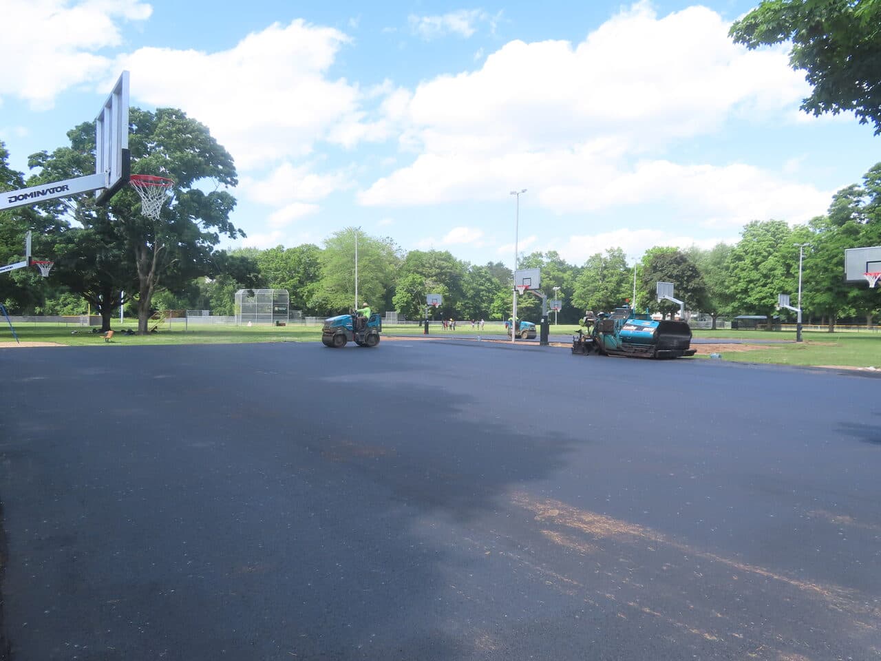 Parking Lot & Athletic Surface Base Paving project in East Hartford, CT — roller and paver compacting asphalt