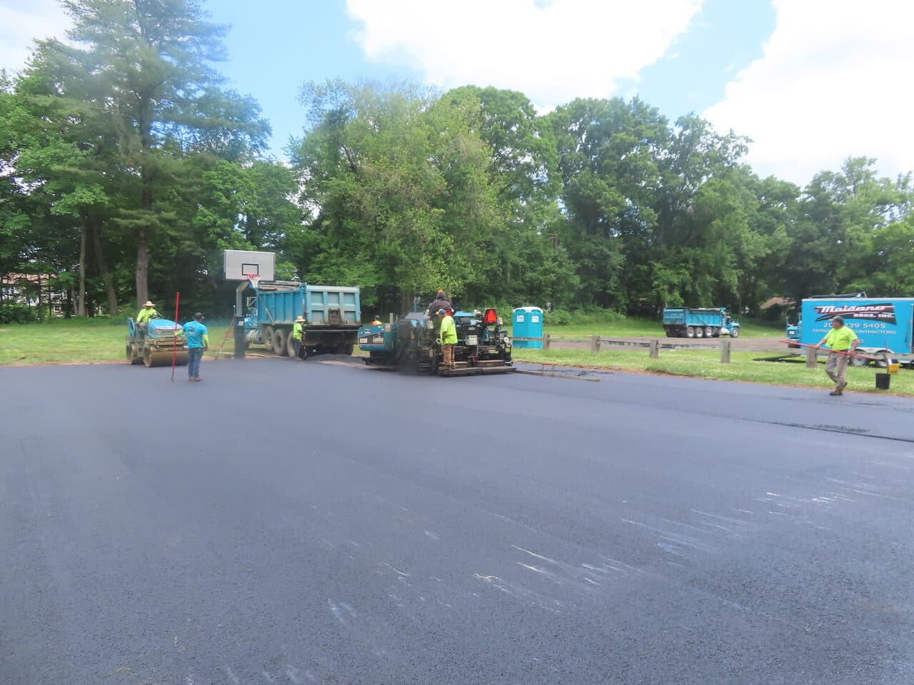 Parking Lot & Athletic Surface Base Paving project in East Hartford, CT — paving crew with roller and trucks