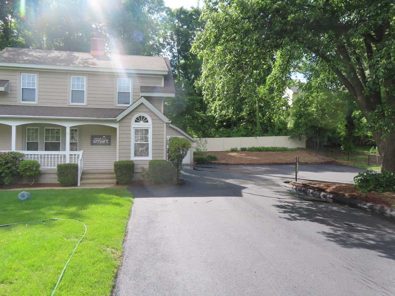 Commercial Driving School Parking Lot Paving project in Hamden, CT — fresh asphalt driveway beside house