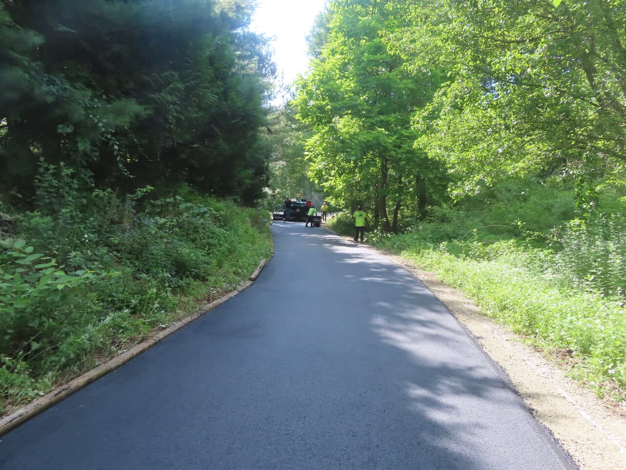Multi-Stop Residential Driveway Paving project in Durham & Wallingford, CT — fresh paved private road through woods