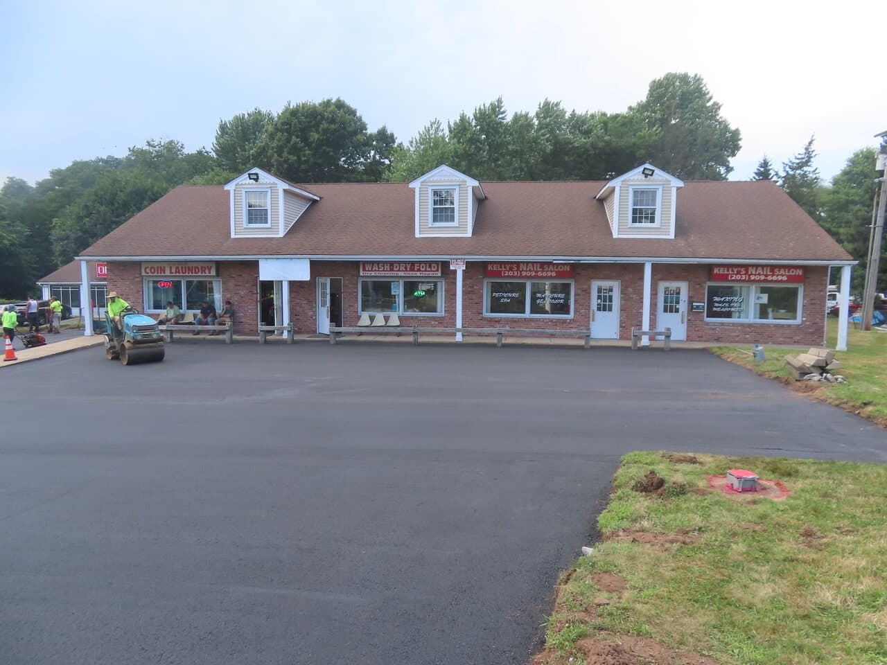 Commercial Plaza Paving project in New Haven, CT — fresh paved lot with roller at strip mall