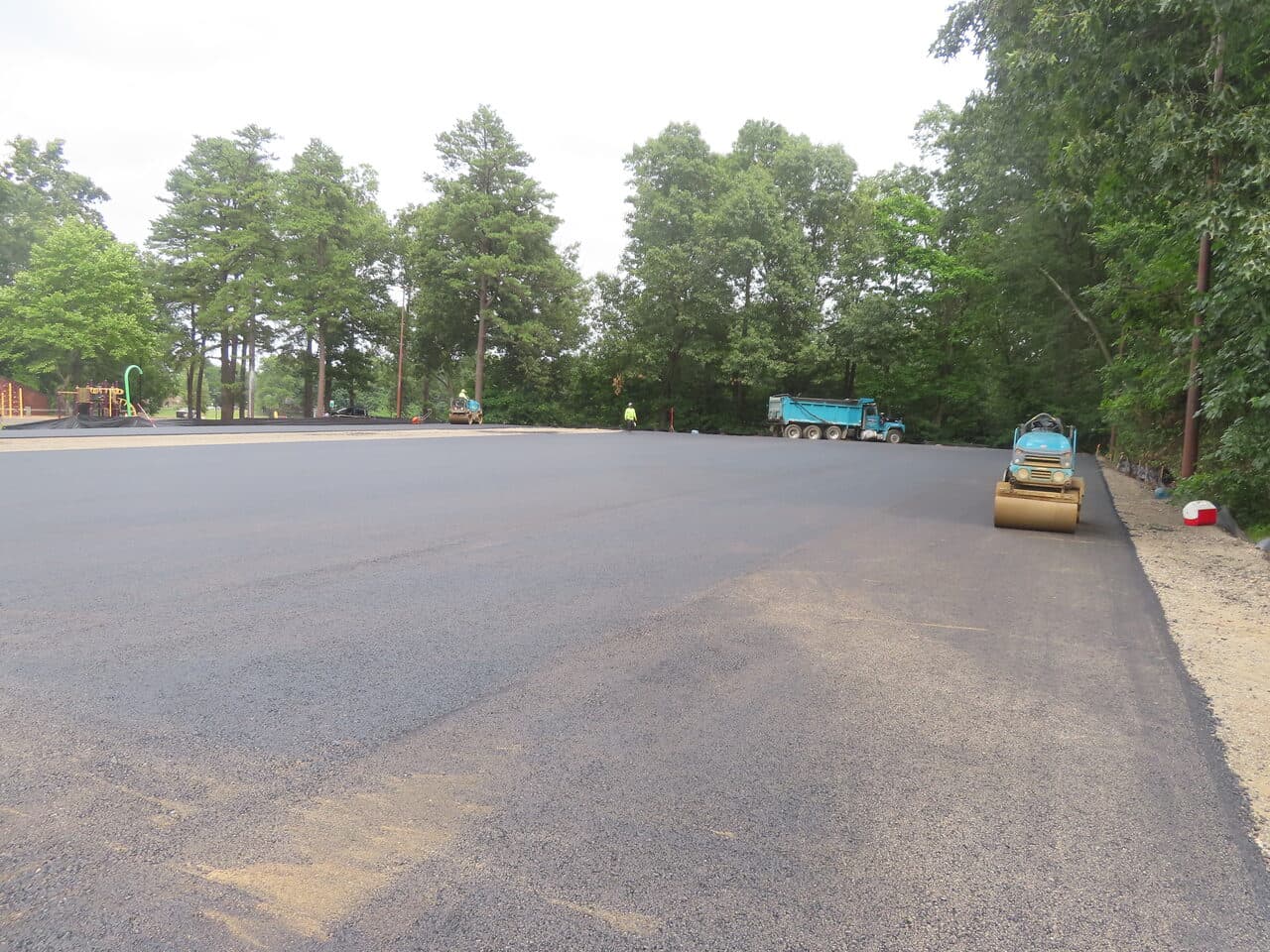 Commercial Parking Lot Paving project in Springfield, MA — fresh asphalt lot with roller compacting