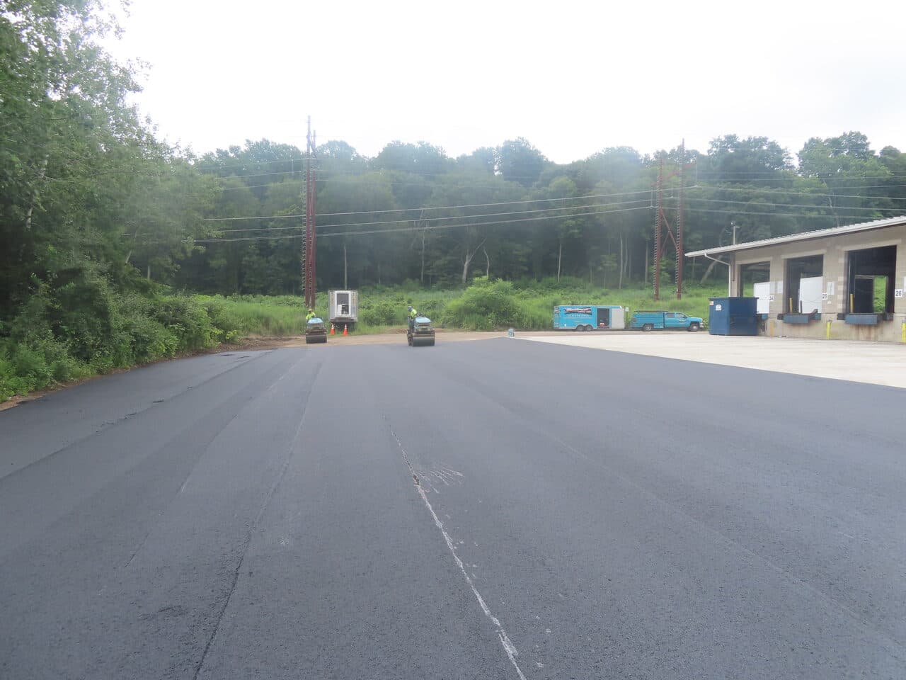Commercial Parking Lot Paving project in Northford, CT — finished asphalt with rollers near dock