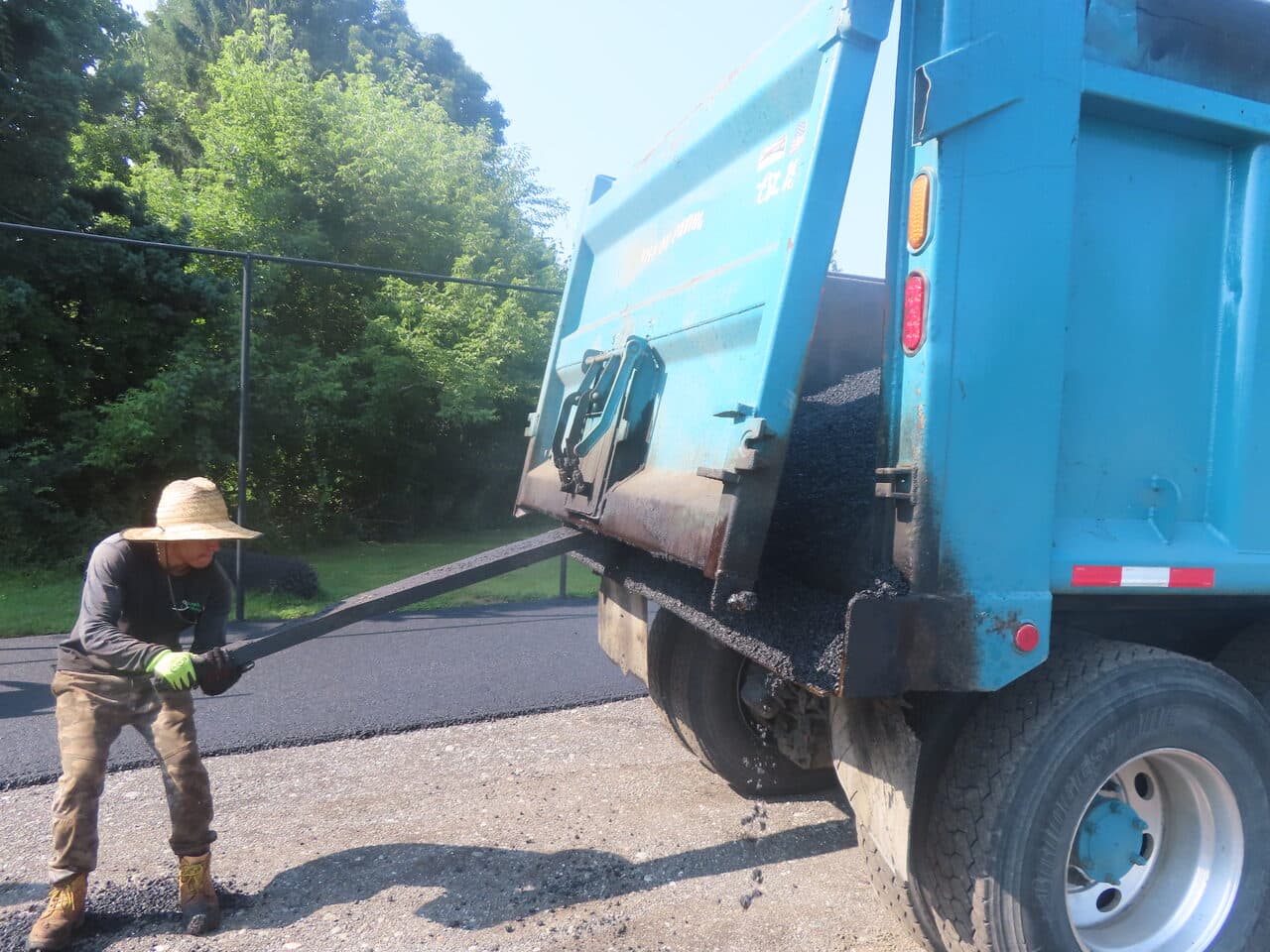 Commercial Parking Lot Paving project in Barrington, RI — worker raking asphalt from truck