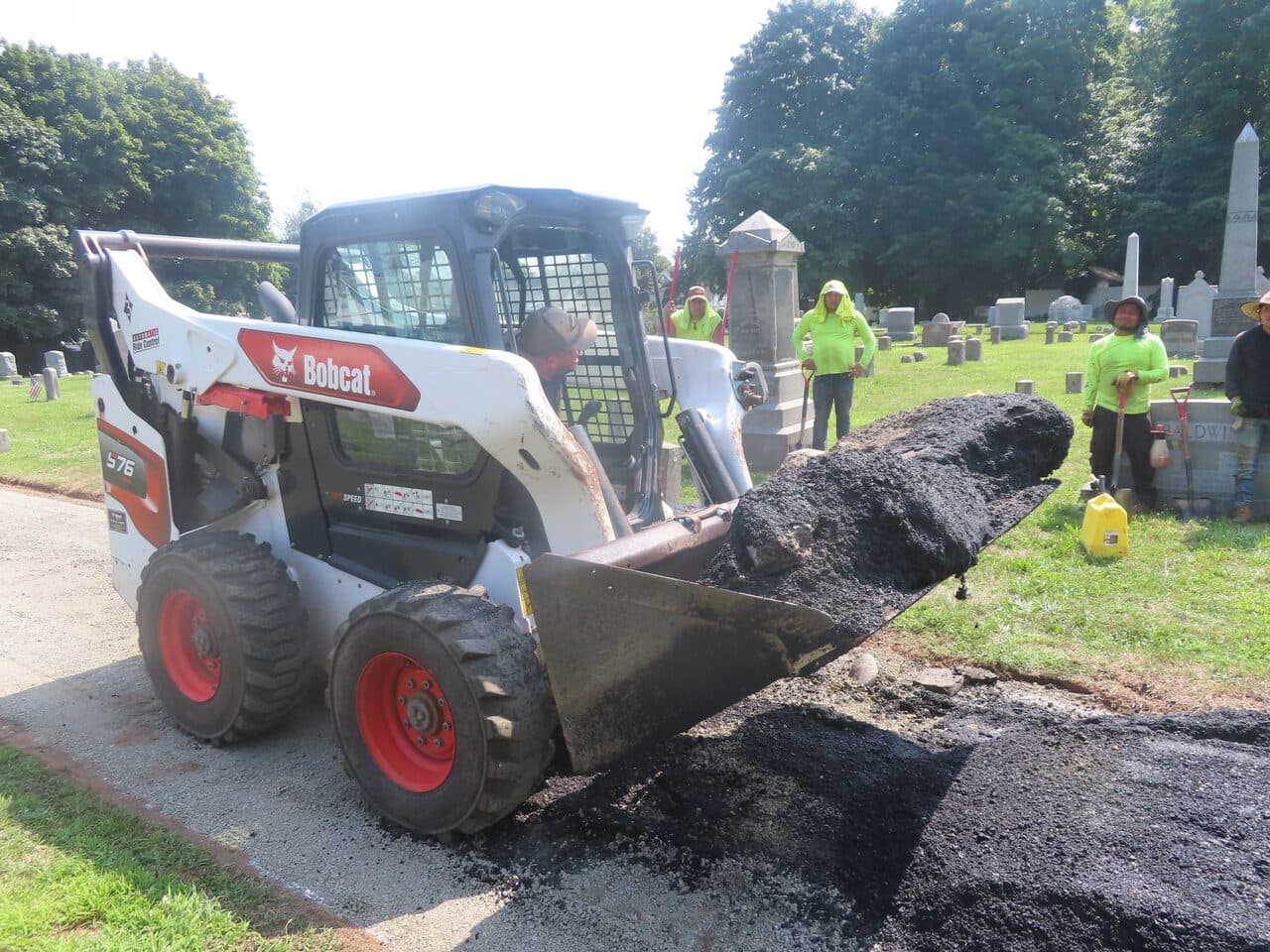 Cemetery Roadway & Walkway Paving project in East Haven, CT — bobcat moving asphalt with workers