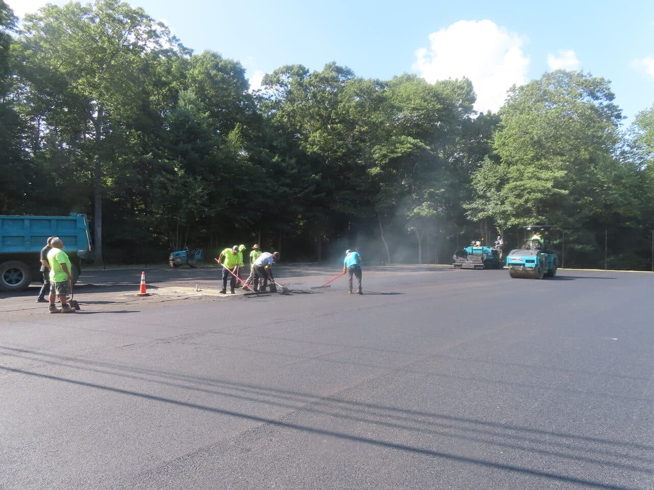 Commercial Parking Lot Paving project in Barrington, RI — crew patching with roller distant