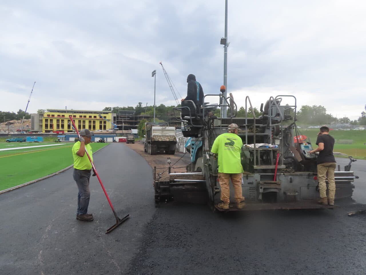 Athletic Surface Base Paving project in Burlington, VT — paver and crew on track cloudy