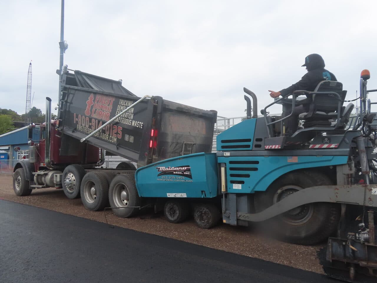 Athletic Surface Base Paving project in Burlington, VT — truck feeding Maisano paver closeup