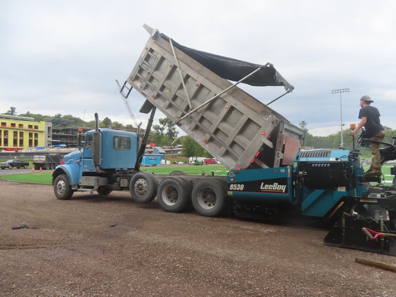 Athletic Surface Base Paving project in Burlington, VT — dump truck raising bed by paver