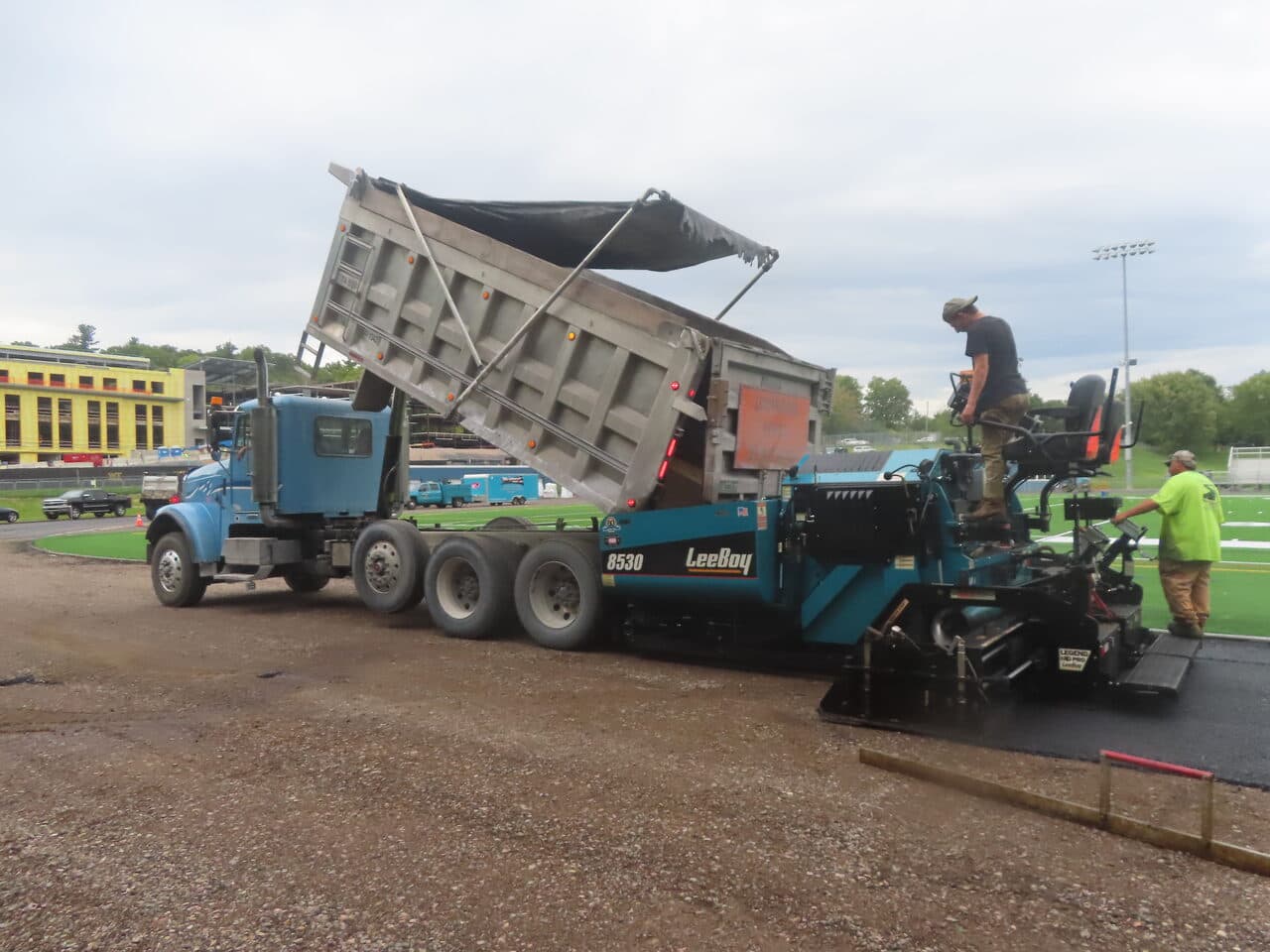 Athletic Surface Base Paving project in Burlington, VT — LeeBoy paver and dump truck
