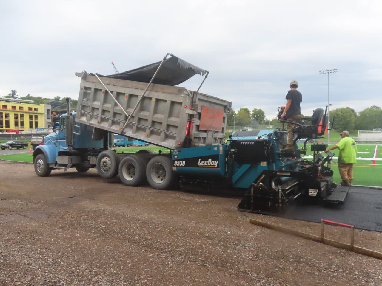 Athletic Surface Base Paving project in Burlington, VT — dump truck feeding LeeBoy paver