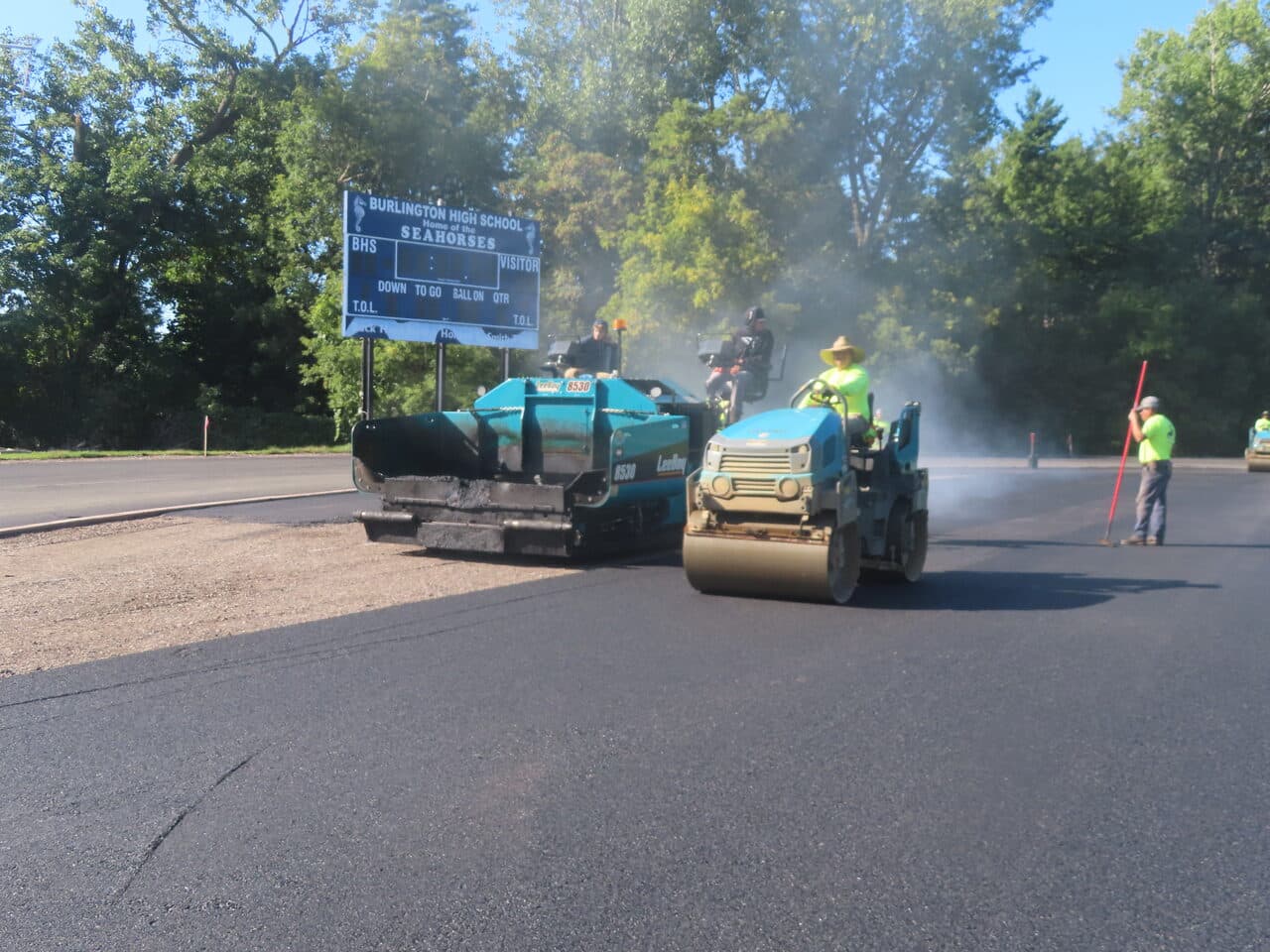 Athletic Surface Base Paving project in Burlington, VT — paver and roller on track