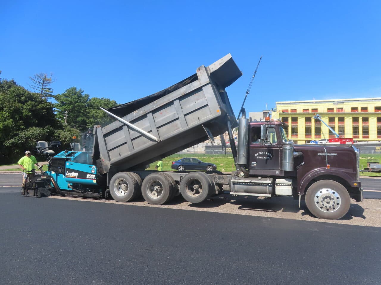Athletic Surface Base Paving project in Burlington, VT — paver and dump truck side view