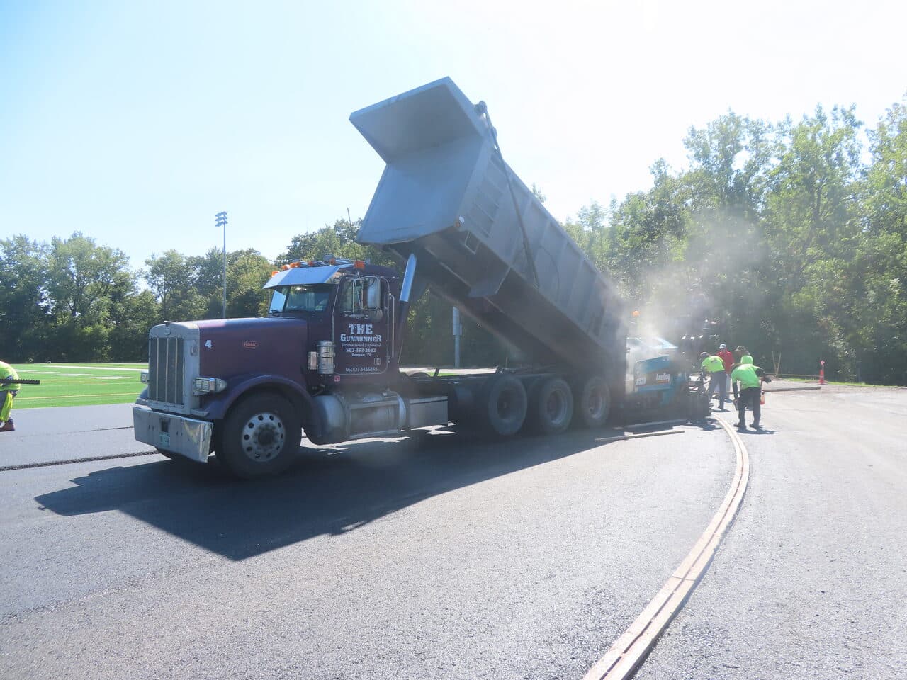 Athletic Surface Base Paving project in Burlington, VT — dump truck dumping into paver