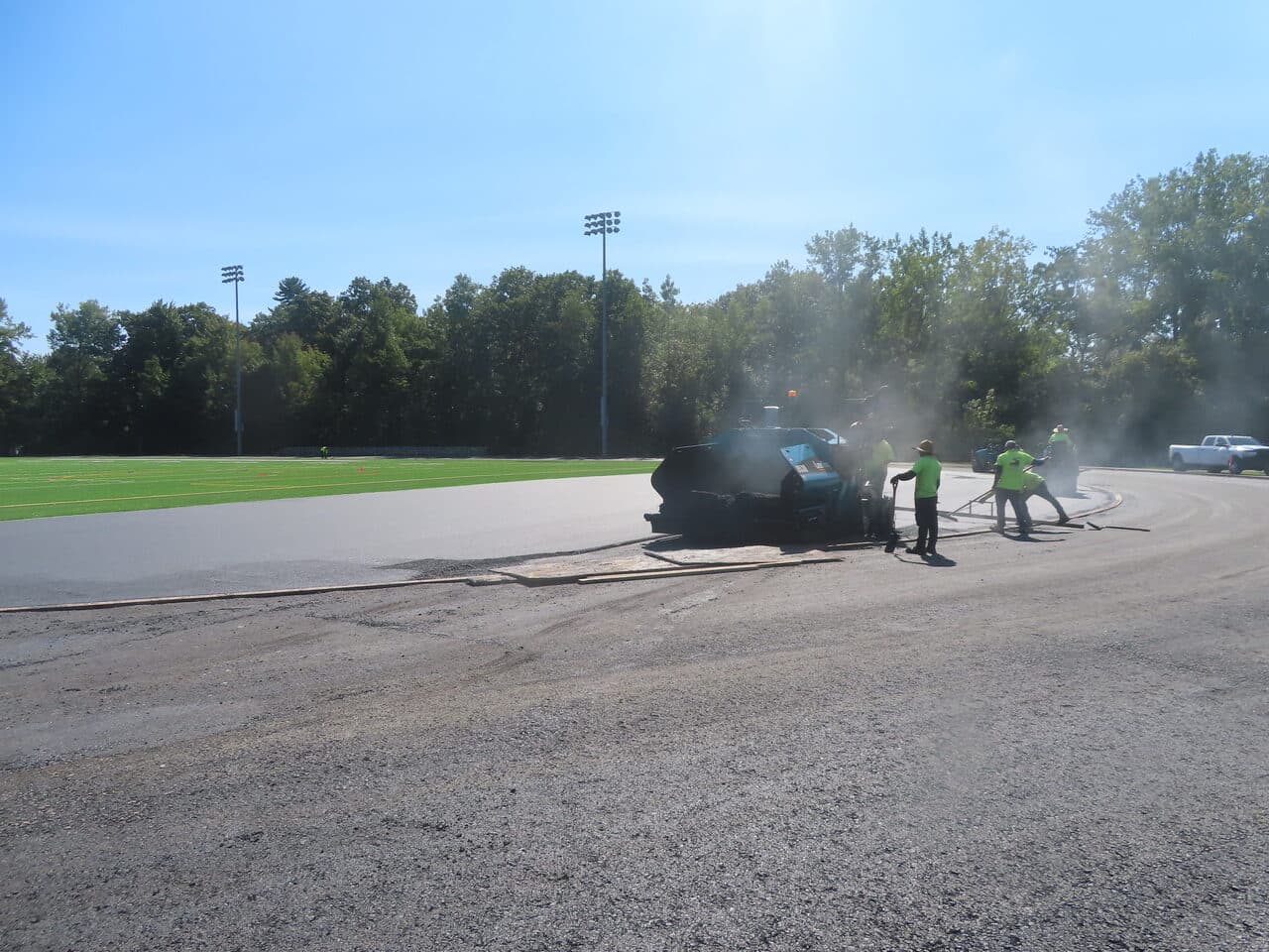 Athletic Surface Base Paving project in Burlington, VT — paver crew on track curve