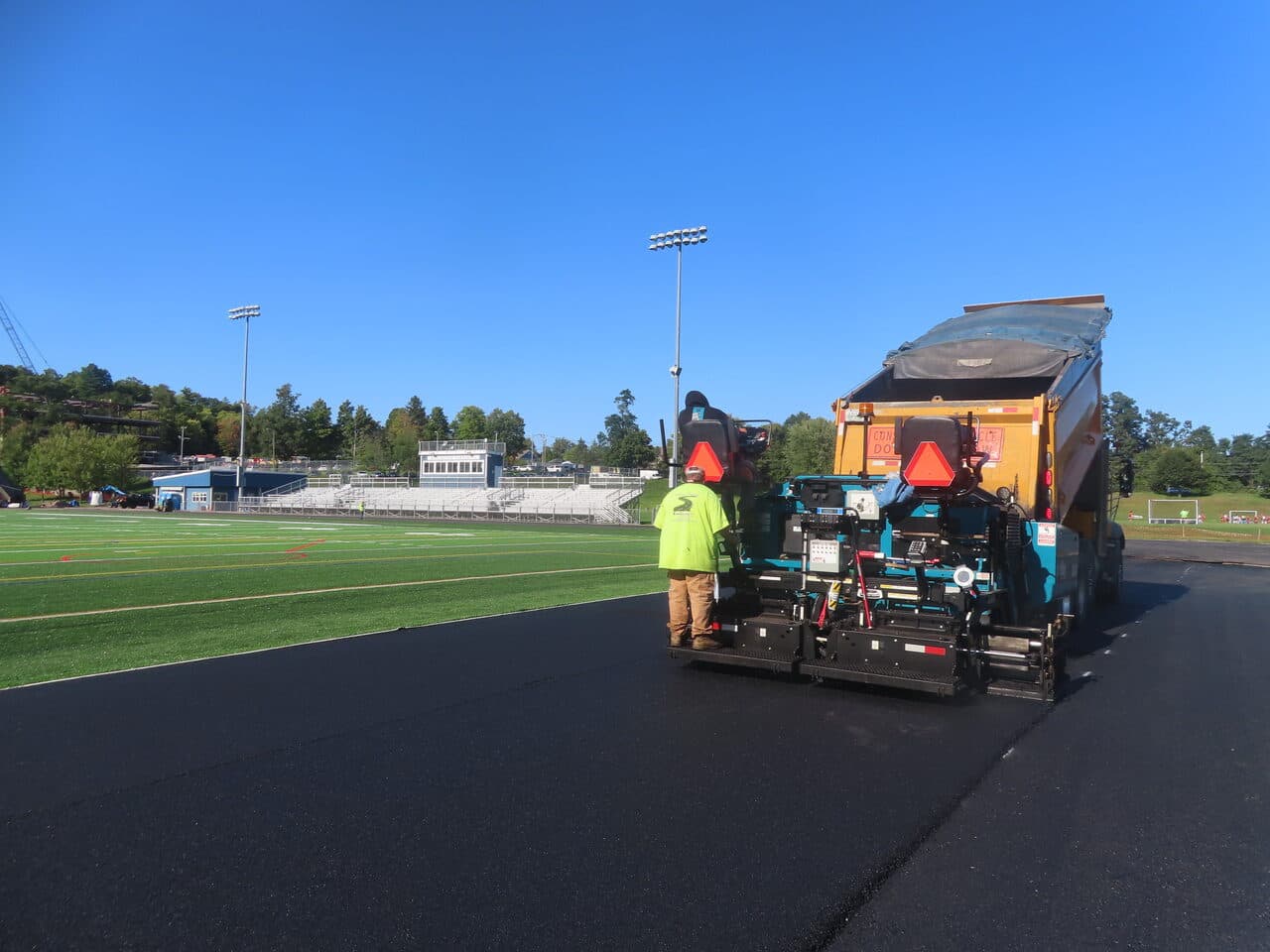 Athletic Surface Base Paving project in Burlington, VT — paver beside bleachers and field