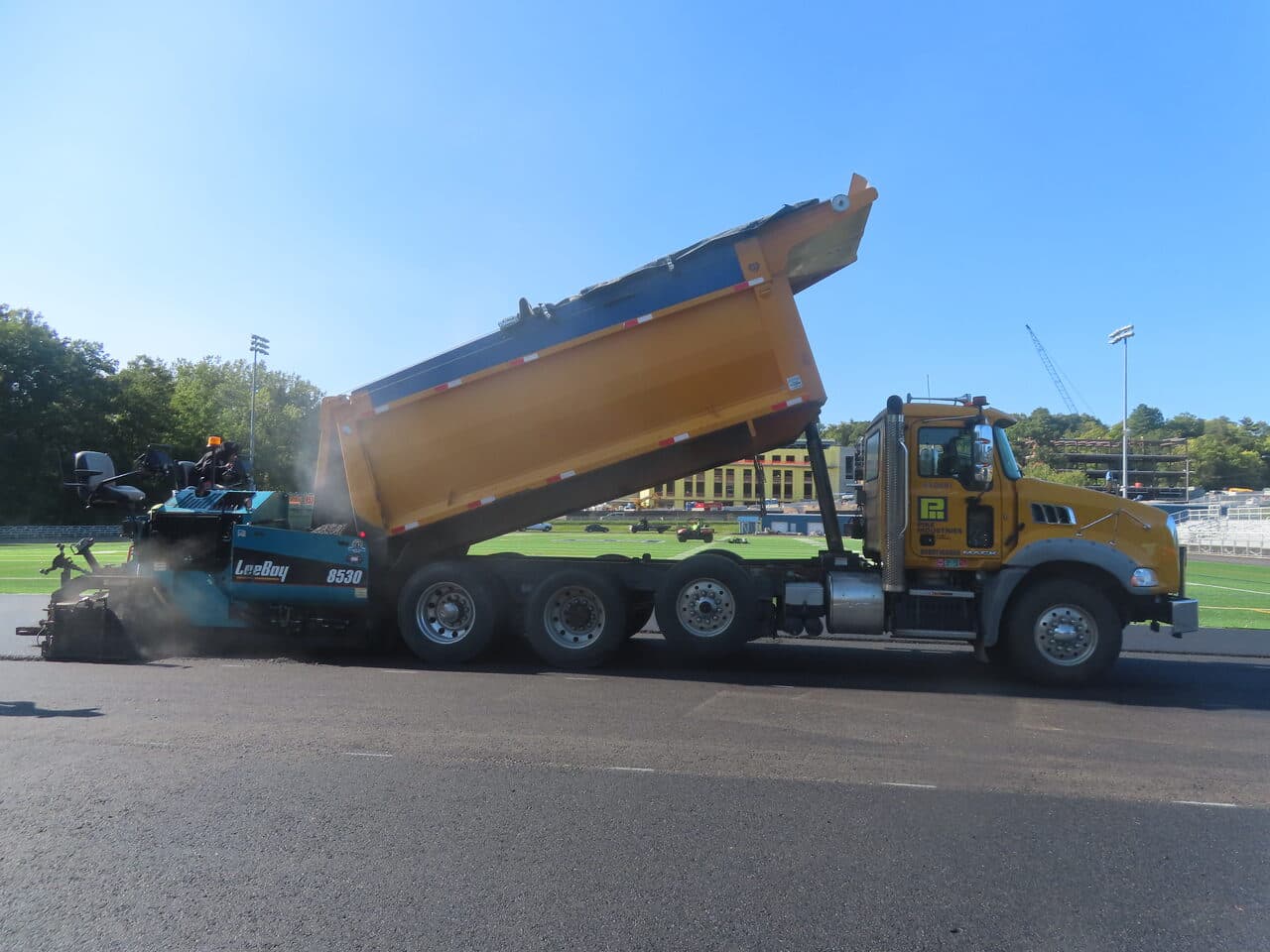 Athletic Surface Base Paving project in Burlington, VT — dump truck and LeeBoy paver