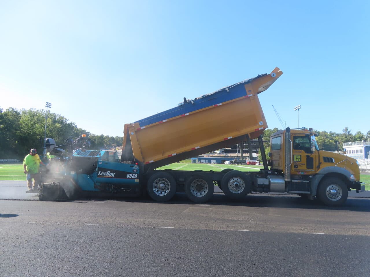 Athletic Surface Base Paving project in Burlington, VT — dump truck dumping into paver